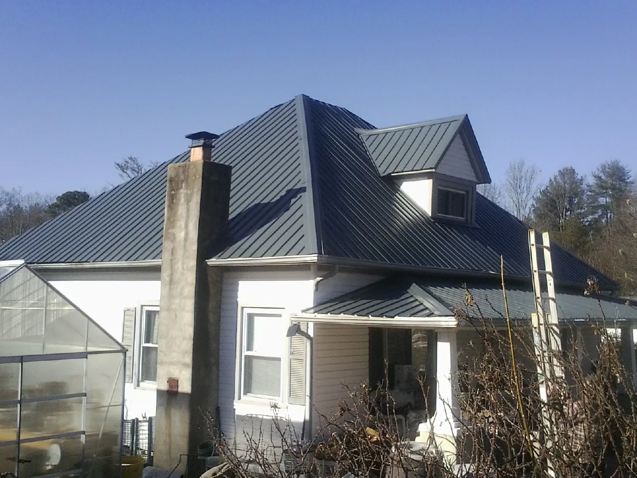 Dark blue standing seam metal roof on a white farmhouse with dormer — Slate & Tile Roof Repair by Roofing Brothers in Wood Dale