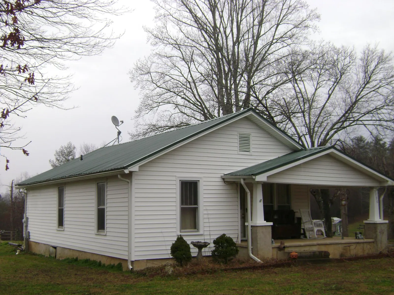 Green metal roof on a white bungalow with a side porch in Wood Dale