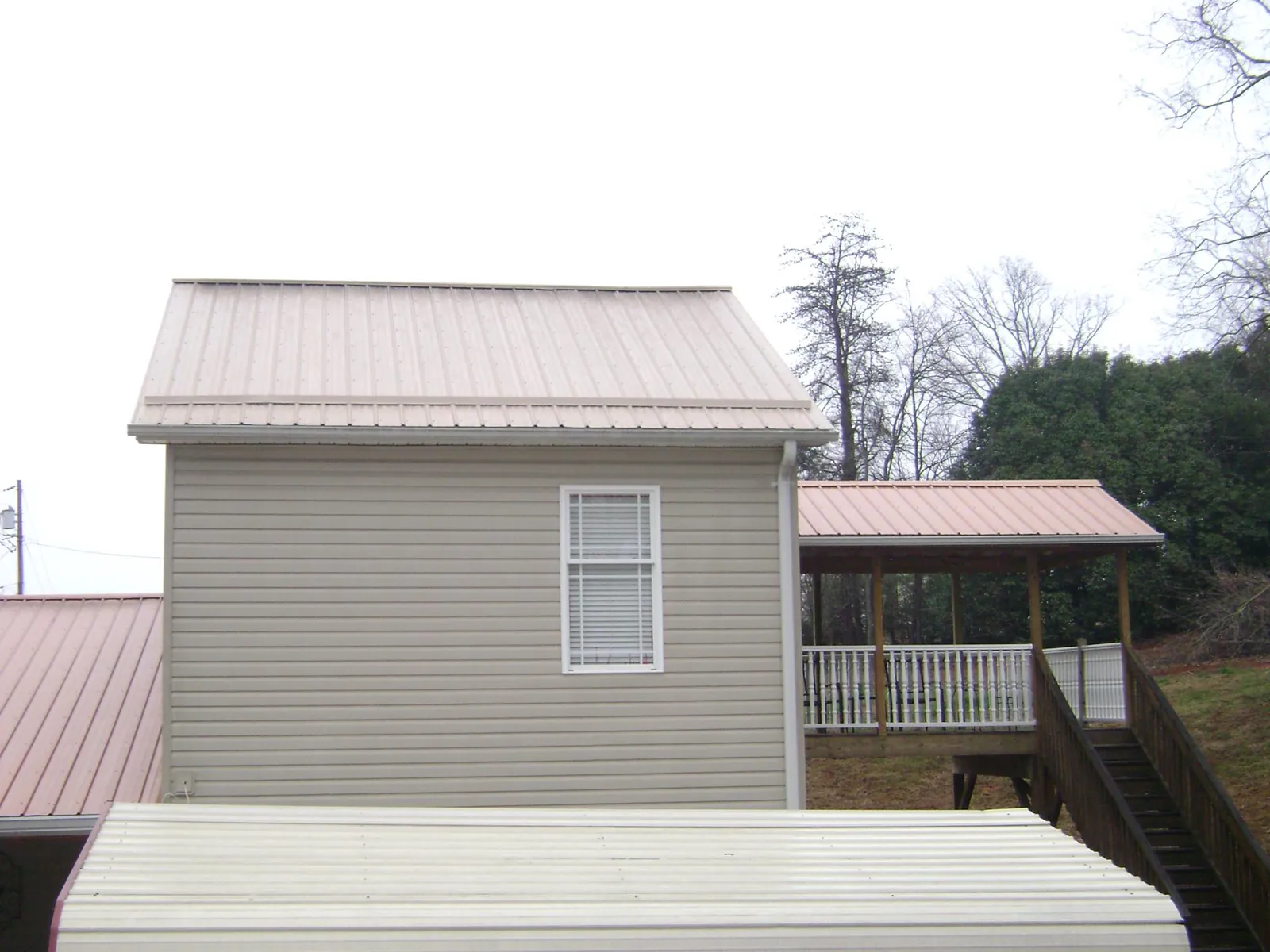 Tan metal roofs on a two story addition and attached porch, from a Roof Replacement job in Wood Dale
