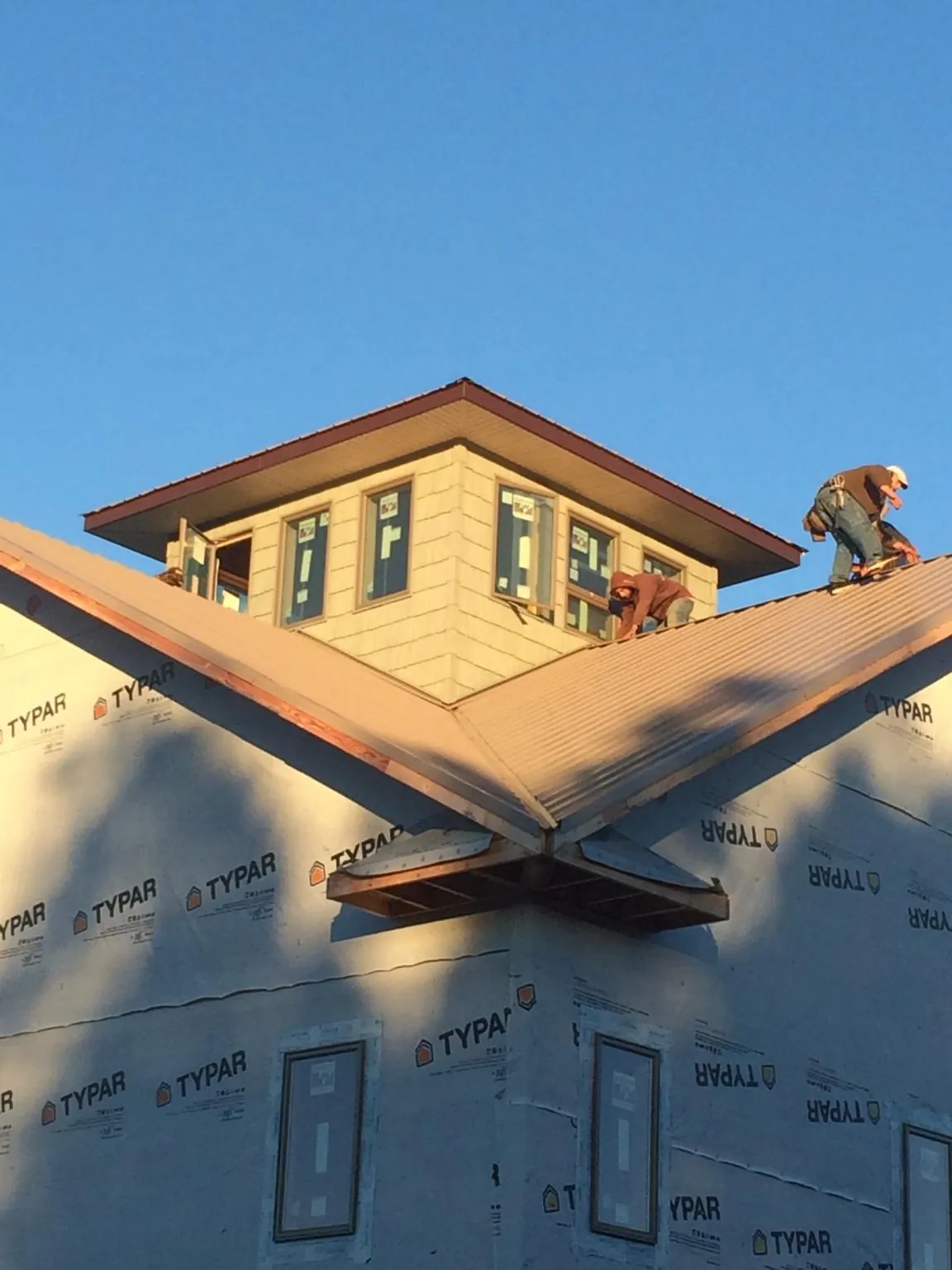 Roofers working around a rooftop cupola on a new metal roof at sunset — Roof Waterproofing in Wood Dale by Roofing Brothers